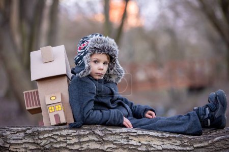 Photo for Little child, blond boy with pet dog, carying home on his back, kid, having paper house, emotional shot - Royalty Free Image