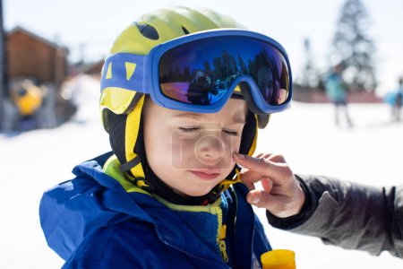 Foto de Madre, la aplicación de crema solar en su hijo de esquí, la familia en las vacaciones de esquí de invierno, el esquí, tomar medidas contra el sol duro en las montañas - Imagen libre de derechos