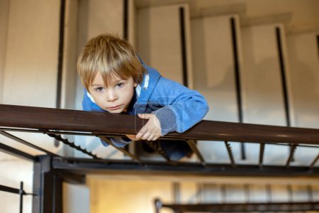 Photo for Spiral staircase in a bluildin, child, standing on the lower floor, looking at camera, view from above - Royalty Free Image