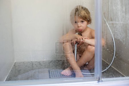 Photo for Blond child, sweet toddler boy in bathroom, taking shower, sitting on the floor, punished - Royalty Free Image