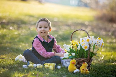 Foto de Hermoso niño pequeño con estilo, niño, jugando con la decoración de Pascua en el parque, primavera - Imagen libre de derechos