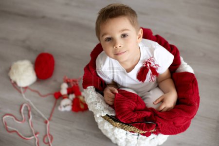 Foto de Lindo niño, niño rubio, jugando con brazalete blanco y rojo, martenitsa bulgara - Imagen libre de derechos