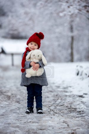 Foto de Hermoso niño pequeño, lindo niño, jugando en el parque nevado tiempo de invierno, día nublado - Imagen libre de derechos