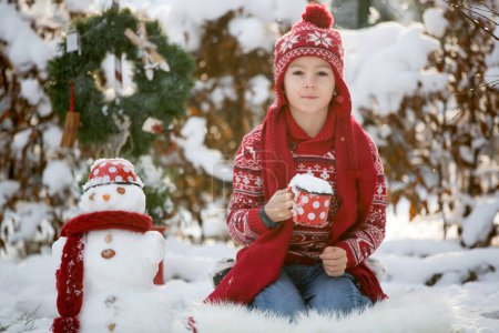Téléchargez les photos : Doux écolier, garçon, jouant dans le jardin avec la neige, faisant bonhomme de neige, enfant heureux temps d'hiver à l'extérieur - en image libre de droit