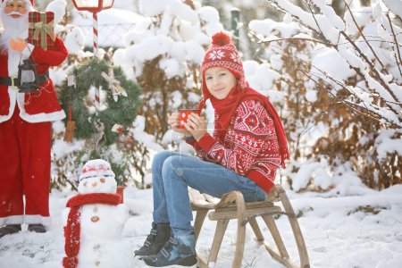 Photo for Sweet school child, boy, playing in garden with snow, making snowman, happy kid winter time outdoors - Royalty Free Image