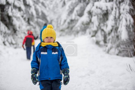 Téléchargez les photos : Doux enfant heureux, jouant dans la neige profonde dans la forêt - en image libre de droit