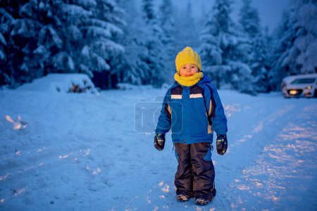 Foto de Dulce niño feliz, jugando en la nieve profunda en el bosque - Imagen libre de derechos