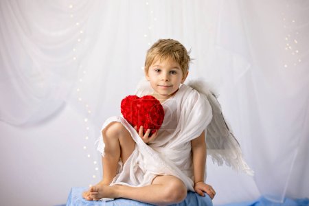 Téléchargez les photos : Little cupid toddle boy, holding bow and arrow, beautiful blond cherub, love - en image libre de droit