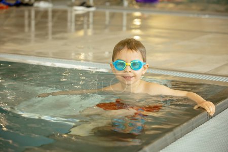 Téléchargez les photos : Enfant, prendre des cours de natation dans un groupe d'enfants dans la piscine intérieure, profiter de l'apprentissage - en image libre de droit