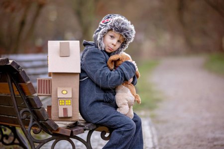 Téléchargez les photos : Little child, blond boy with pet dog, carying home on his back, kid, having paper house, emotional shot - en image libre de droit