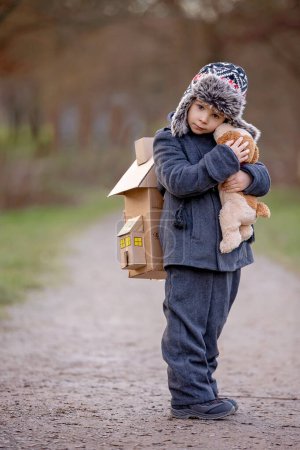 Téléchargez les photos : Little child, blond boy with pet dog, carying home on his back, kid, having paper house, emotional shot - en image libre de droit
