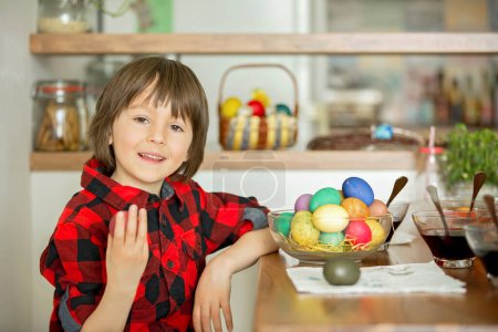 Téléchargez les photos : Deux enfants, garçons, colorier les œufs de Pâques à la maison, manger des fraises - en image libre de droit