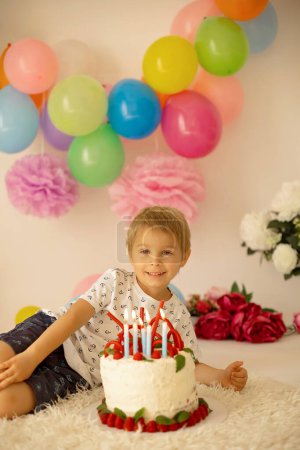 Téléchargez les photos : Enfant mignon, garçon d'âge préscolaire, fête anniversaire à la maison avec gâteau fait maison avec framboises, menthe et bonbons, ballons et décoration dans la chambre - en image libre de droit