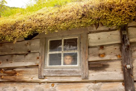 Photo for Amazing little wooden small house next to a waterfall on the dock of Hellesylt, child playing in the house, looking out of the window - Royalty Free Image