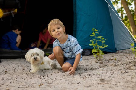 Photo for Happy family, three kids, boy brothers and a dog,playing around pitched tent on the beach, while wild camping in Norway, summertime - Royalty Free Image