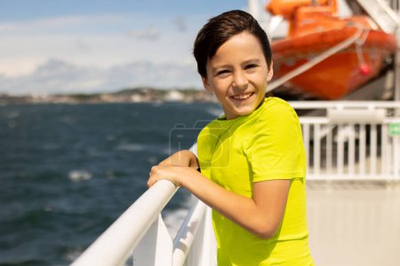 Foto de Children, experience ride with ferry on a fjord, strong wind on the deck of the ferry on a sunny day - Imagen libre de derechos