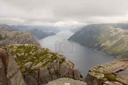Foto de Family, enjoying the hike to Preikestolen, the Pulpit Rock in Lysebotn, Norway on a rainy day, toddler climbing with his pet dog the one of the most scenic fjords in Norway - Imagen libre de derechos