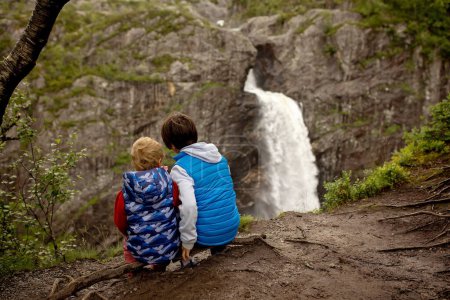 Foto de Happy european family with kids and dog, enjoying the hike to Manafossen waterfall summertime on a cold day - Imagen libre de derechos