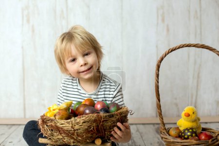 Foto de Dulce niño pequeño, lindo niño jugando con coloridos huevos de Pascua, disparo de estudio - Imagen libre de derechos