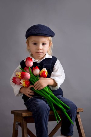 Photo for Beautiful toddler boy, hodling lilies and tulips as present for mother's day - Royalty Free Image