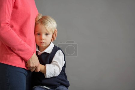 Téléchargez les photos : Triste petit enfant, garçon, embrassant sa mère à la maison, image isolée, espace de copie. Concept de famille - en image libre de droit