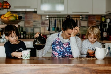Photo for Tired mother, trying to pour coffee in the morning. Woman lying on kitchen table after sleepless night, trying to drink coffee - Royalty Free Image