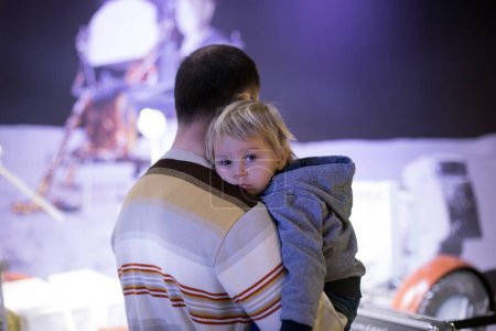 Photo for Cute little toddler boy, lying on daddy's shoulder, Dad carrying him in a museum, indoors - Royalty Free Image