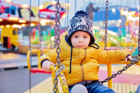 Photo for Child, cute boy riding chain swing carousel on sunset, motion blur, colorful background - Royalty Free Image