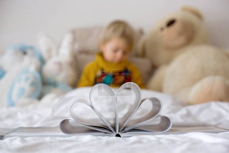 Photo for Beautiful child, toddler boy, reading book and playing with it, creative knowledge shot with book and letters - Royalty Free Image