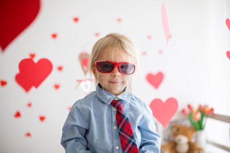 Foto de Lindo niño rubio, sosteniendo el juguete del corazón y jugando con corazones para San Valentín. sé mi niño de San Valentín - Imagen libre de derechos