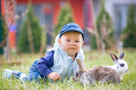 Photo for Cute little baby boy, child playing little bunny in park, outdoors - Royalty Free Image
