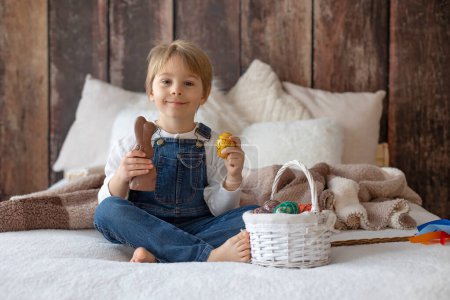 Photo for Sweet preschool boy in studio, playing with, egg for Easter and eating chocolate, child on Easter holiday at home - Royalty Free Image