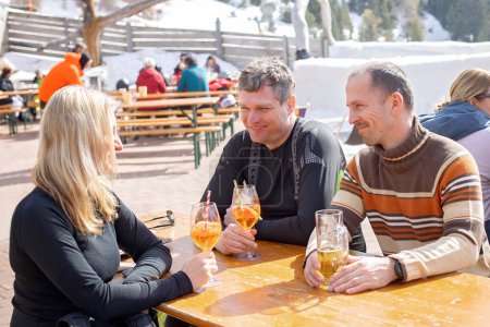 Photo for Happy family, enjoying ski holiday with children, sunny beautiful weather outdoors, people drinking aperol spritz on a sunny day - Royalty Free Image