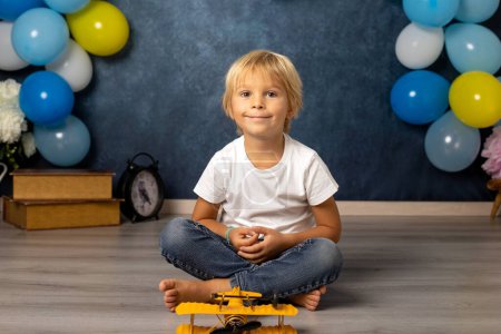 Foto de Lindo niño preescolar, jugando con el avión, globos y decoración de cumpleaños en el fondo - Imagen libre de derechos