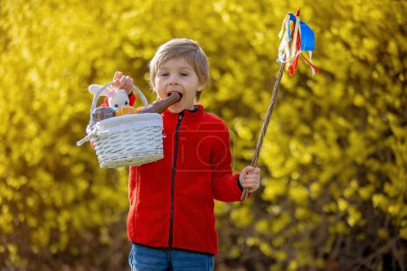 Foto de Cute preschool child, boy, holding handmade braided whip made from pussy willow, traditional symbol of Czech Easter used for whipping girls and women to receive eggs and sweets - Imagen libre de derechos