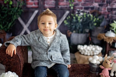 Téléchargez les photos : Enfant tout-petit élégant et mignon, garçon avec chemise blanche, jouant avec des œufs et un lapin en chocolat sur la décoration de Pâques, plan studio - en image libre de droit