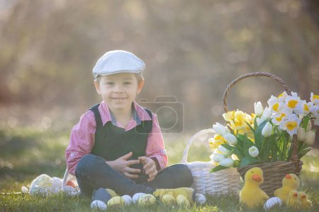 Téléchargez les photos : Beau tout-petit élégant enfant, garçon, jouer avec la décoration de Pâques dans le parc, printemps - en image libre de droit