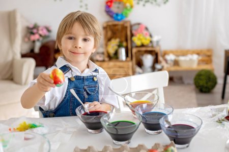 Téléchargez les photos : Happy childen, frères et sœurs, oeufs à colorier avec des eaux colorées pour Pâques à la maison, chambre ensoleillée - en image libre de droit