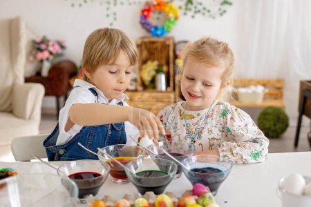 Photo for Happy childen, siblings, coloring eggs with colorful waters for Easter at home, sunny room - Royalty Free Image
