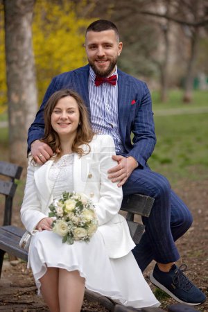Photo for Young newlywed couple, having pictures taken on their wedding outdoors, springtime - Royalty Free Image