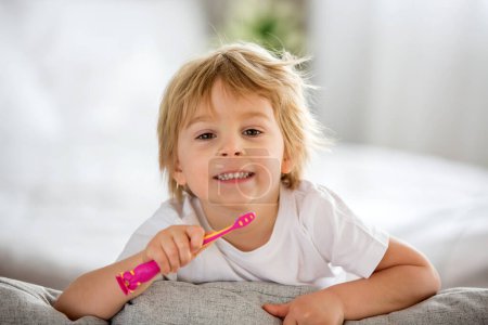 Photo for Cute toddler child, blond boy, brushing his teeth at home, isolated - Royalty Free Image