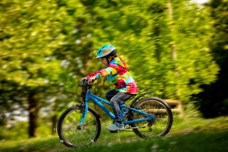 Foto de Niño feliz, divirtiéndose en el parque con una bicicleta en un hermoso día. Niño activo - Imagen libre de derechos