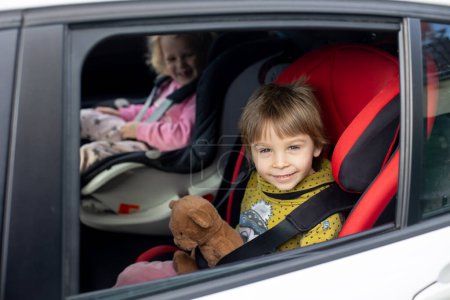 Photo for Cute children, boy and girl siblings, sitting in car seats in car, traveling. Family going to family vacation - Royalty Free Image