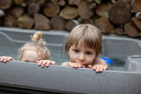 Téléchargez les photos : Enfants, garçons et filles, jouant dans la baignoire d'hydromassage, bain à remous dans la cour arrière de la maison - en image libre de droit
