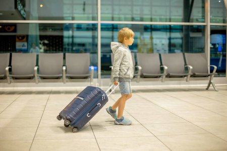 Photo for Children with suitcases at airport, walking at night together, waiting for a flight - Royalty Free Image