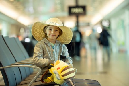 Foto de Niños, hermanos, viajando para vacaciones de verano, esperando en el aeropuerto para abordar el avión - Imagen libre de derechos