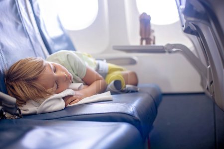 Téléchargez les photos : Mignon enfant d'âge préscolaire, garçon, volant sur un long vol lointain, dormant dans l'avion - en image libre de droit