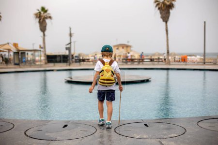 Photo for Cute child, boy, playing with water in fountain in Tel Aviv, lights and colors - Royalty Free Image