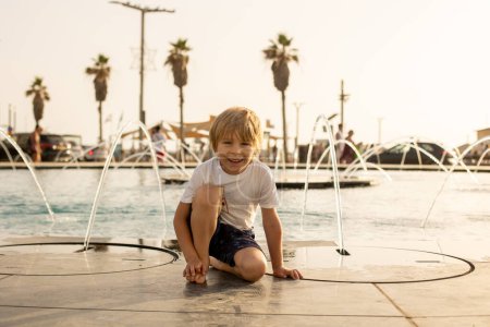 Téléchargez les photos : Enfant mignon, garçon, jouer avec l'eau dans la fontaine à Tel Aviv, lumières et couleurs - en image libre de droit
