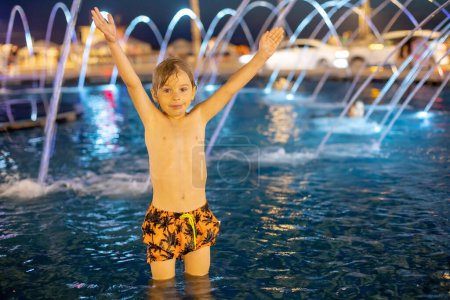 Foto de Lindo niño, niño, jugando con agua en la fuente en Tel Aviv, luces y colores - Imagen libre de derechos